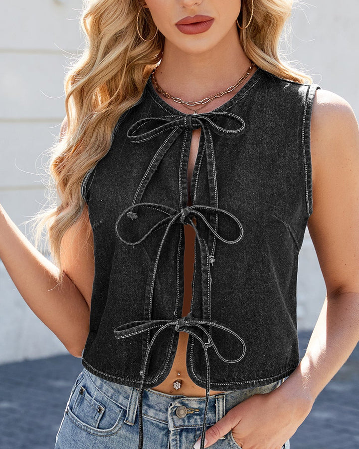 Woman wearing a black sleeveless denim top with a white building background