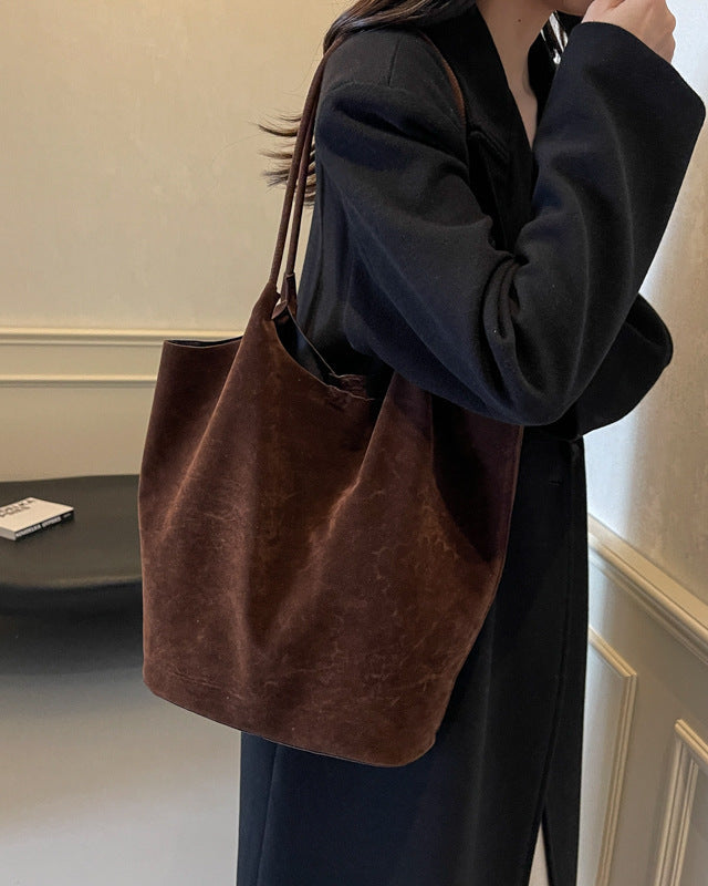 Person holding a brown leather handbag indoors