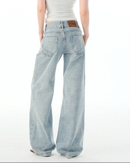 Woman wearing light blue jeans and a white tank top on a white background