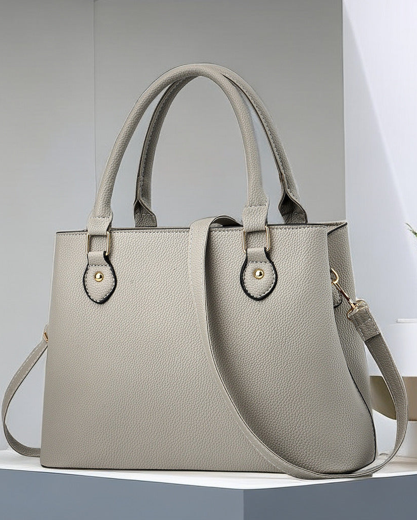 Gray handbag on a white surface with a light gray background