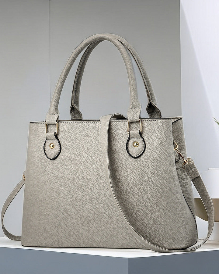 Gray handbag on a white surface with a light gray background
