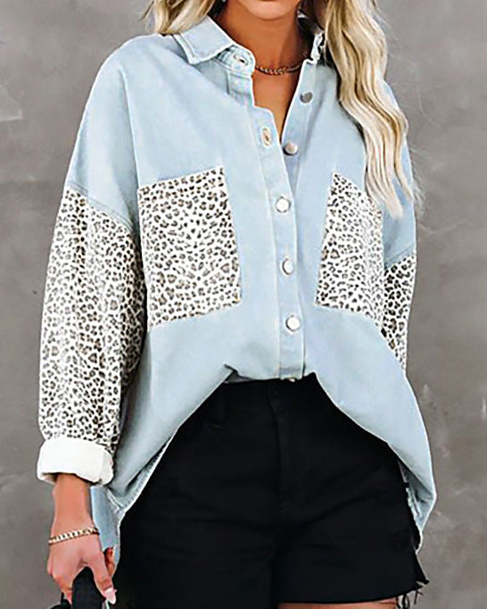 Woman wearing a light blue shirt with leopard print accents and black shorts against a gray background