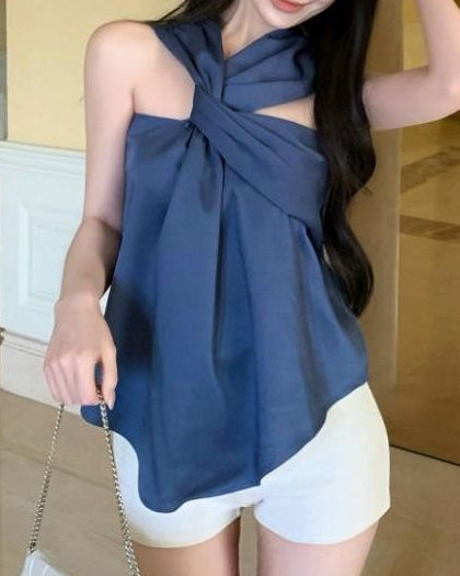 Woman wearing a blue top with a large bow and white shorts in an indoor setting.