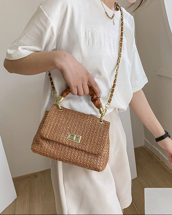 Person holding a brown woven handbag indoors