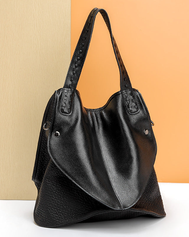 Black leather handbag on a white surface with a beige and orange background