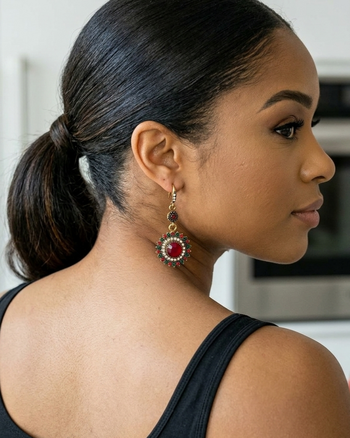 Woman wearing a red and gold earring, side profile view