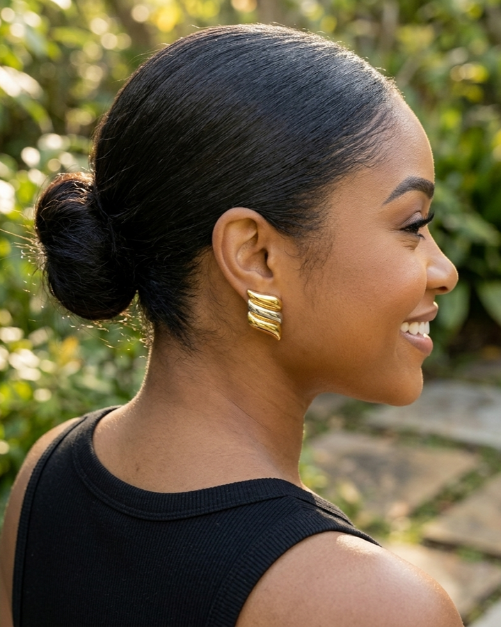 Woman with styled hair and gold earrings outdoors