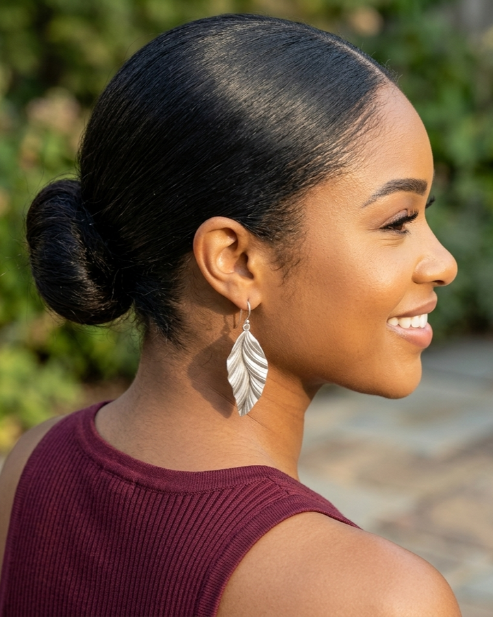 Woman with a stylish hair bun wearing silver earrings outdoors