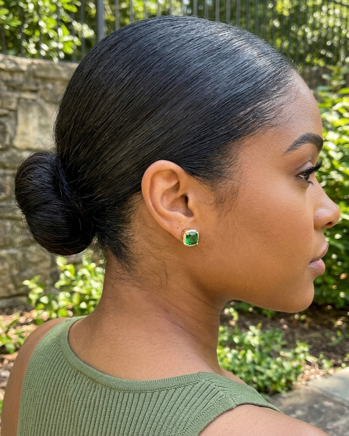 Woman with styled hair and green earrings outdoors
