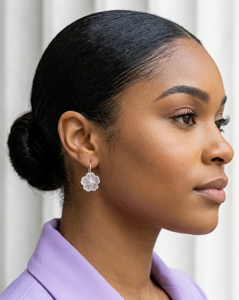 Woman with styled hair wearing floral earrings against a white background