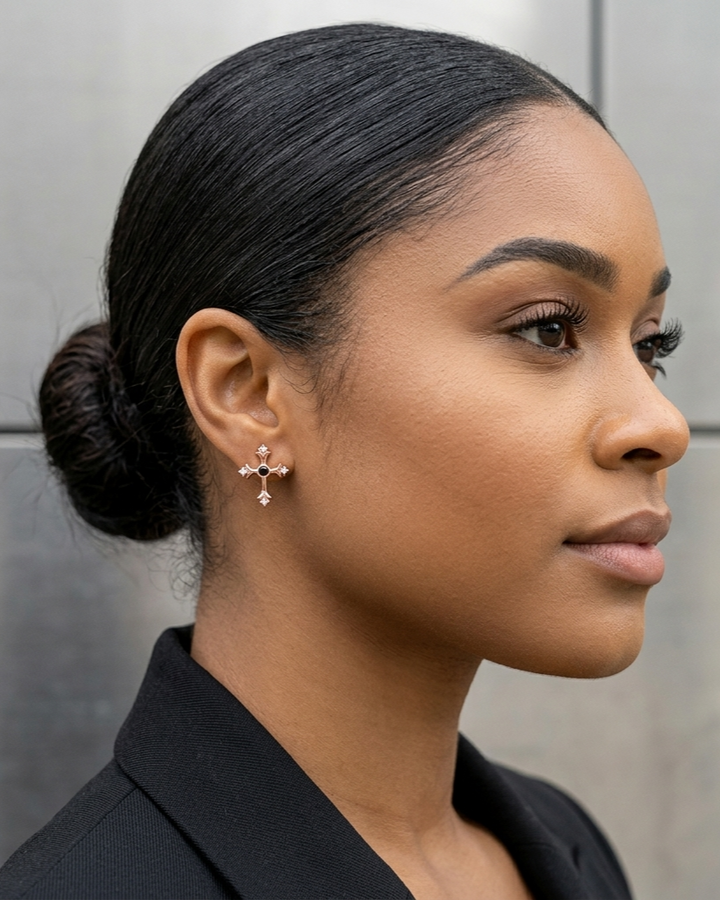Woman with styled hair and earrings against a neutral background