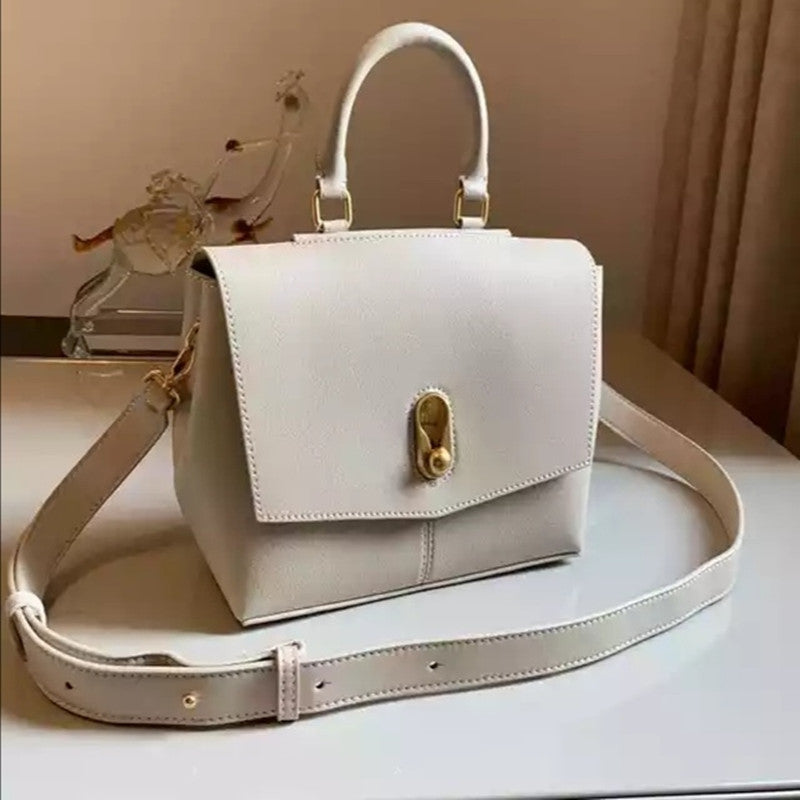 White handbag with gold accents on a light surface