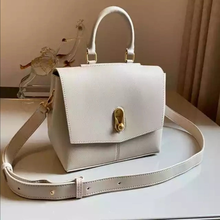 White handbag with gold accents on a light surface