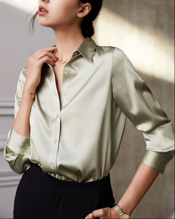 Woman wearing a light green satin shirt against a neutral background
