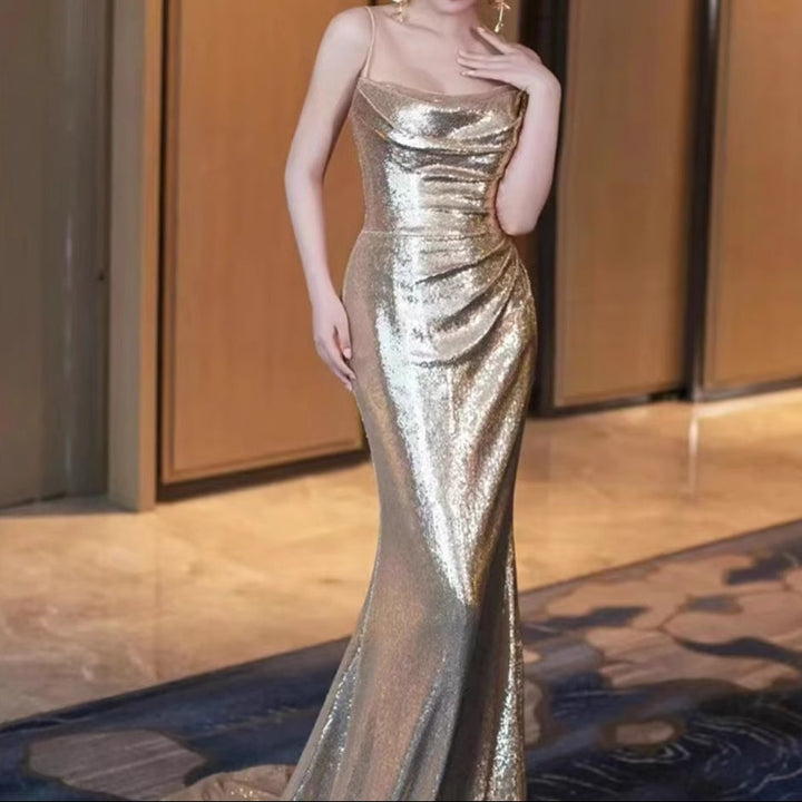 Woman in a gold sequin gown standing indoors with a blurred background