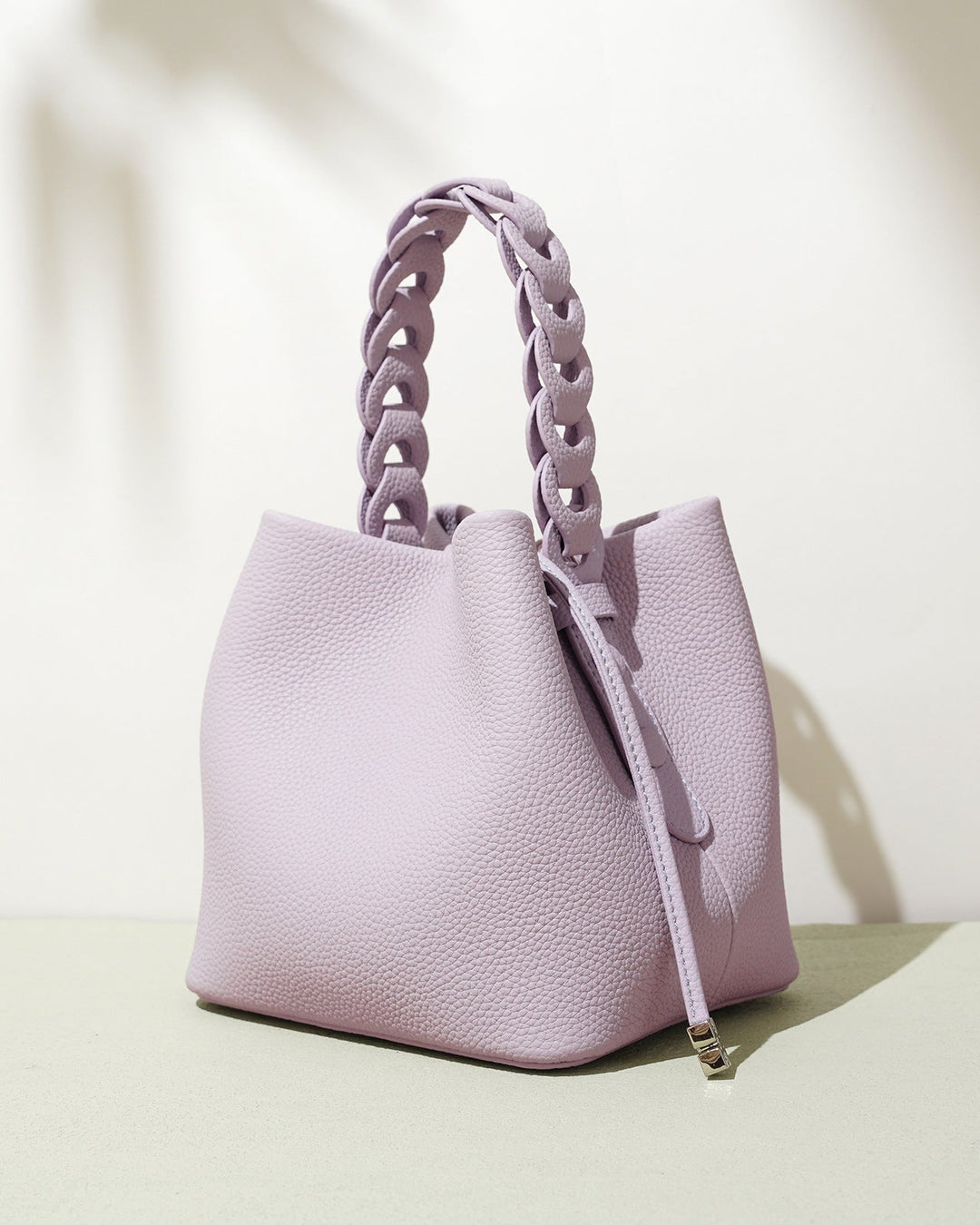 Pink handbag with chain handle on a light background