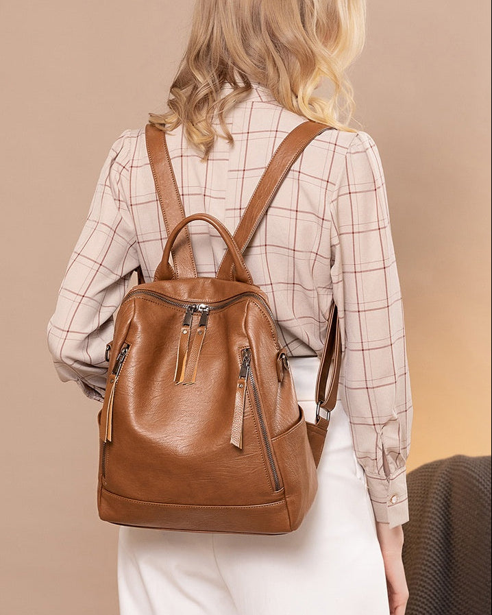 Woman wearing a brown leather backpack against a beige background