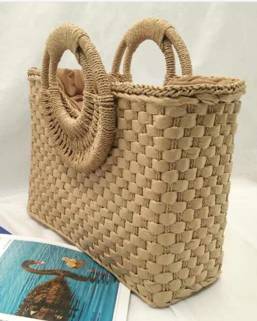 Woven handbag with braided handles on a white background