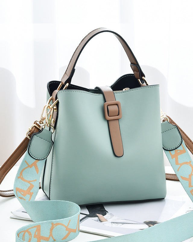 Light blue handbag with brown strap and matching strap on a white surface