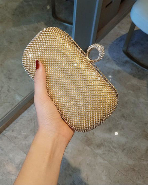 Gold beaded clutch held by a hand on a marble floor