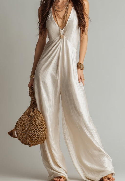 Woman wearing a white jumpsuit holding a woven bag against a neutral background
