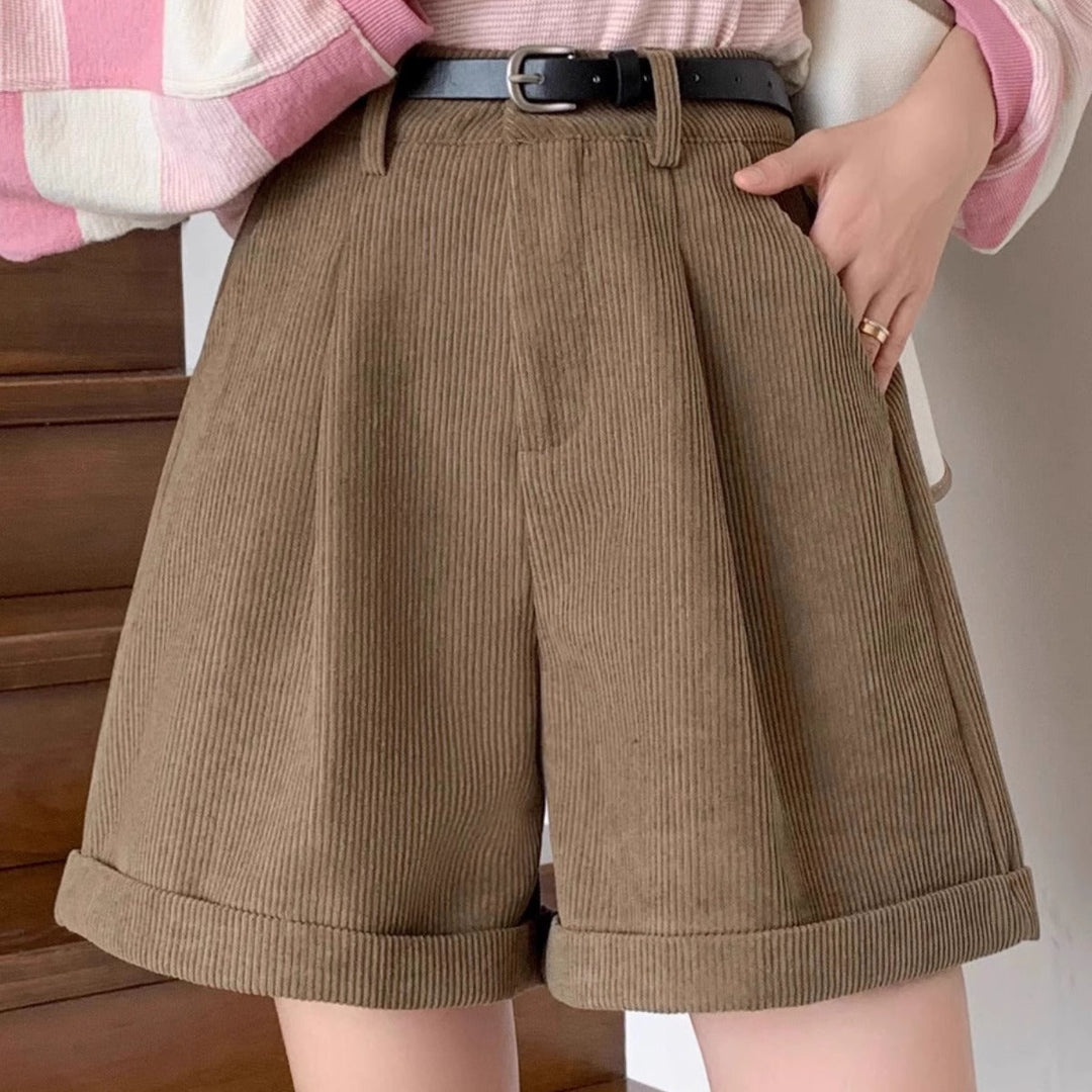 Person wearing a pink and white striped sweater with text, brown shorts, and a black belt.