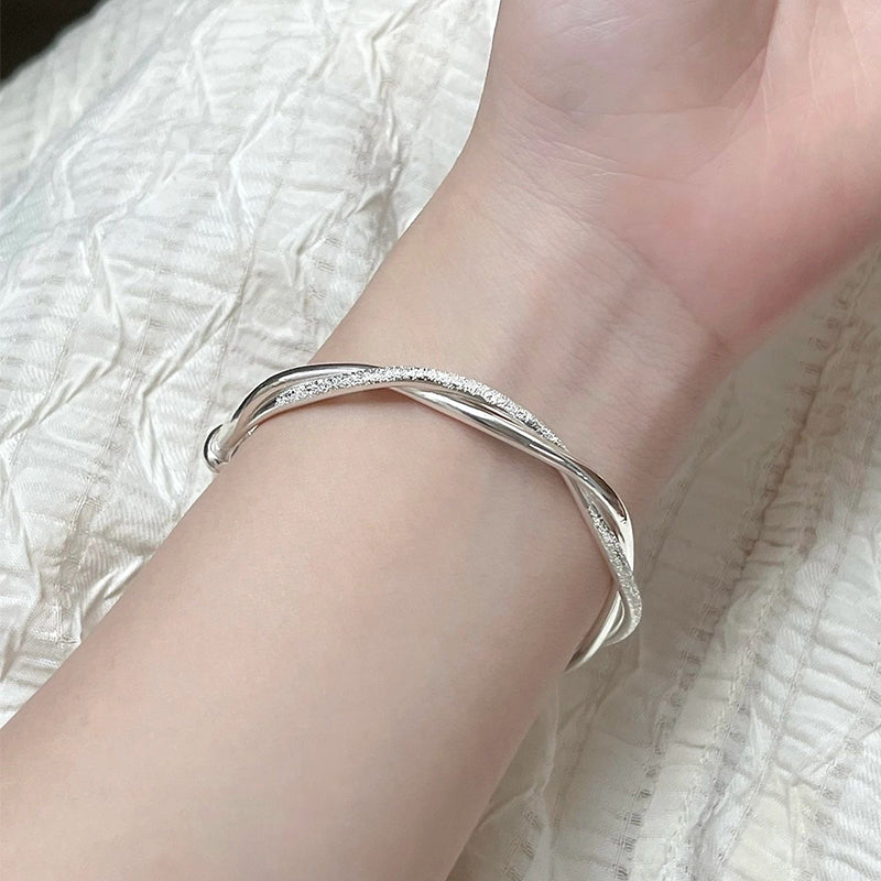 Silver bracelet on a wrist with a white textured fabric background