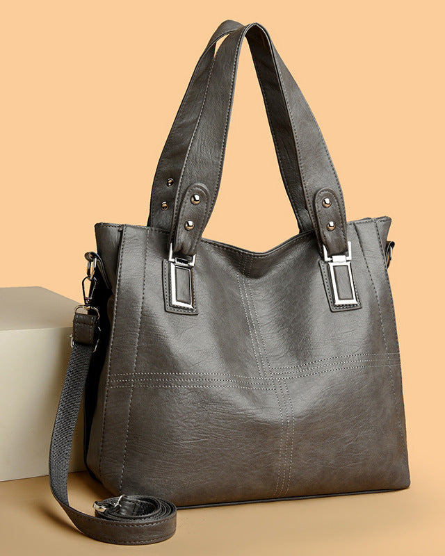 Gray handbag with black straps on a beige background