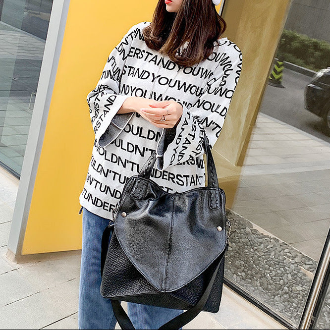 Woman holding a black handbag against a yellow wall