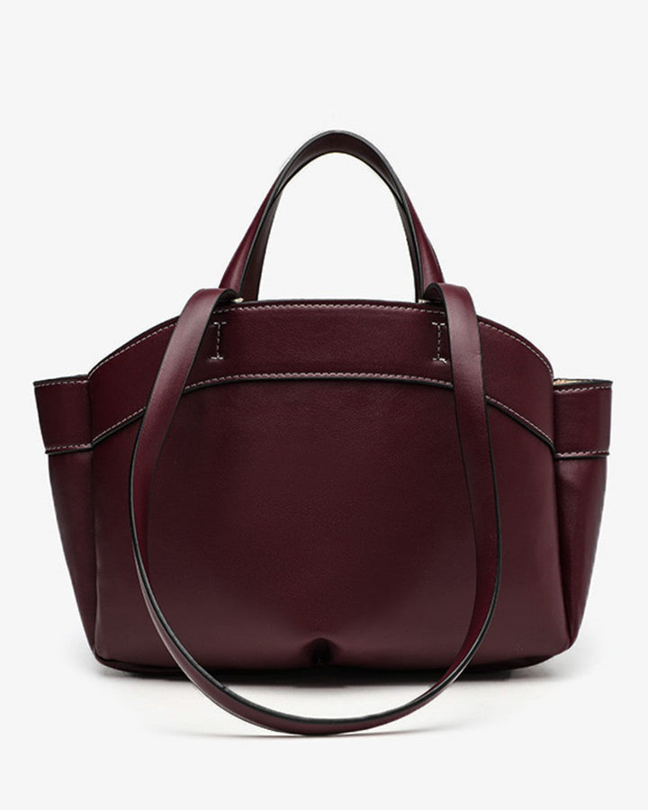 Burgundy handbag with a strap on a white background
