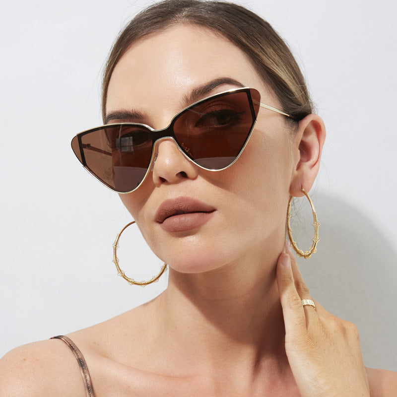 Woman wearing gold hoop earrings and sunglasses against a plain background