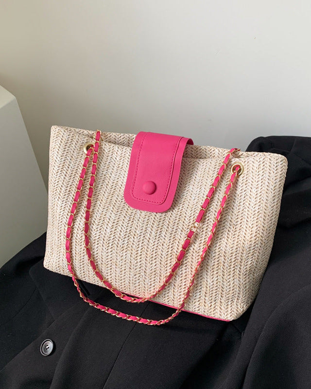 Woven handbag with pink accents on a black surface
