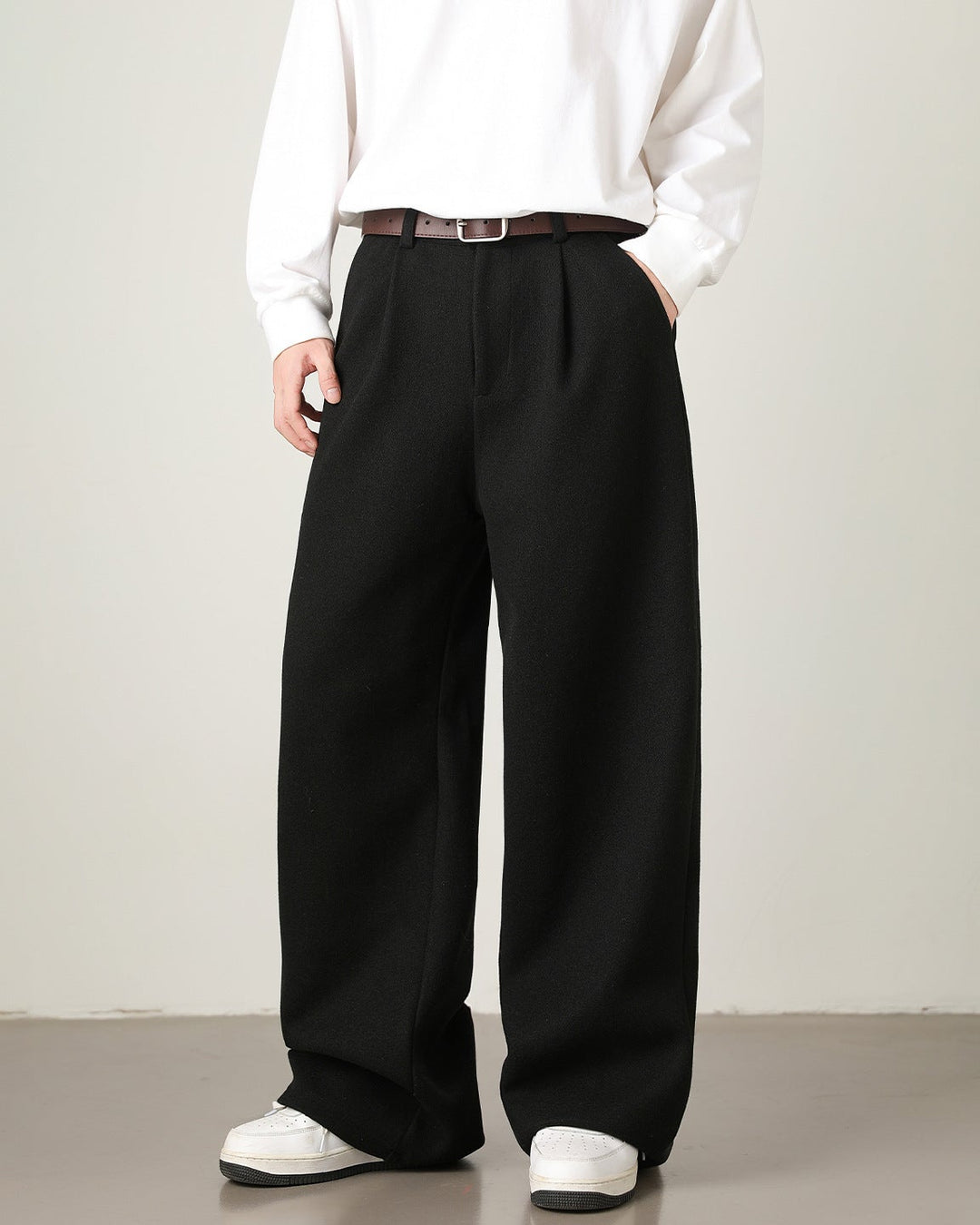 Person wearing a white shirt, black wide-leg pants, and white shoes on a plain background