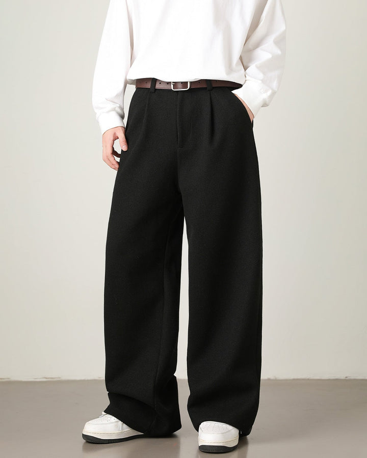 Person wearing a white shirt, black wide-leg pants, and white shoes on a plain background