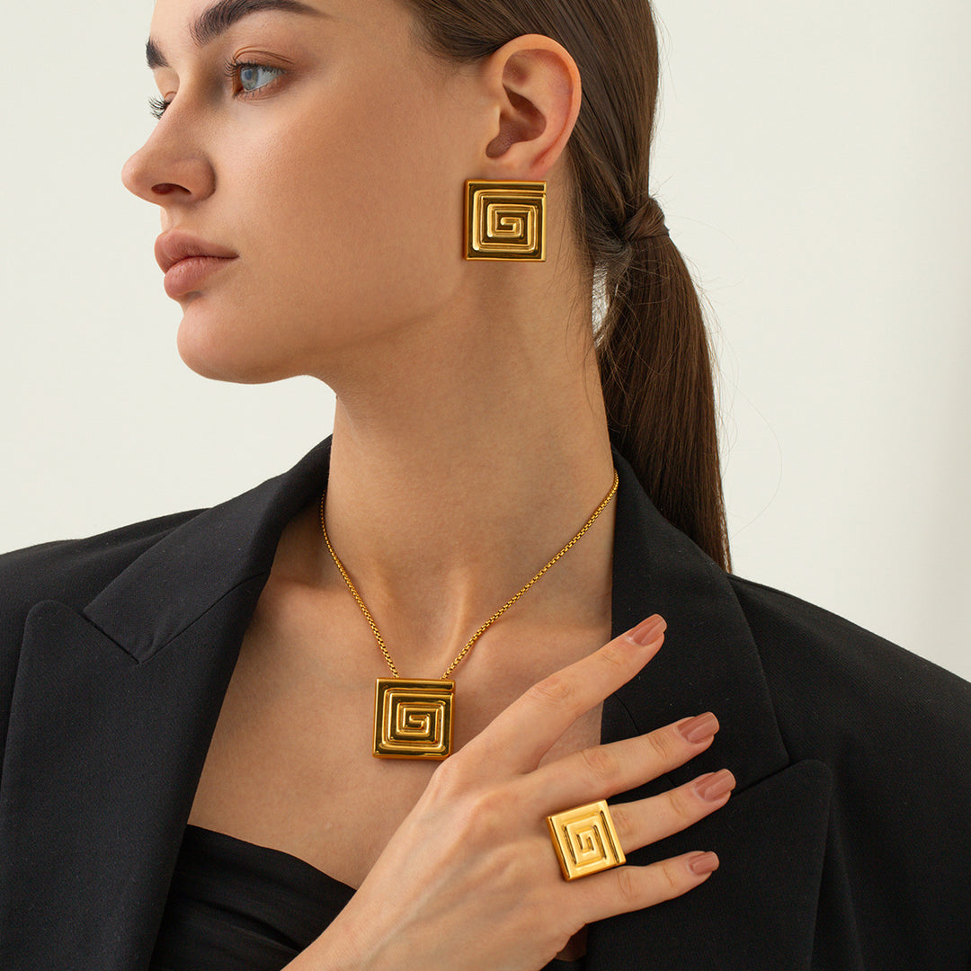Woman wearing gold jewelry including earrings, necklace, and ring on a neutral background