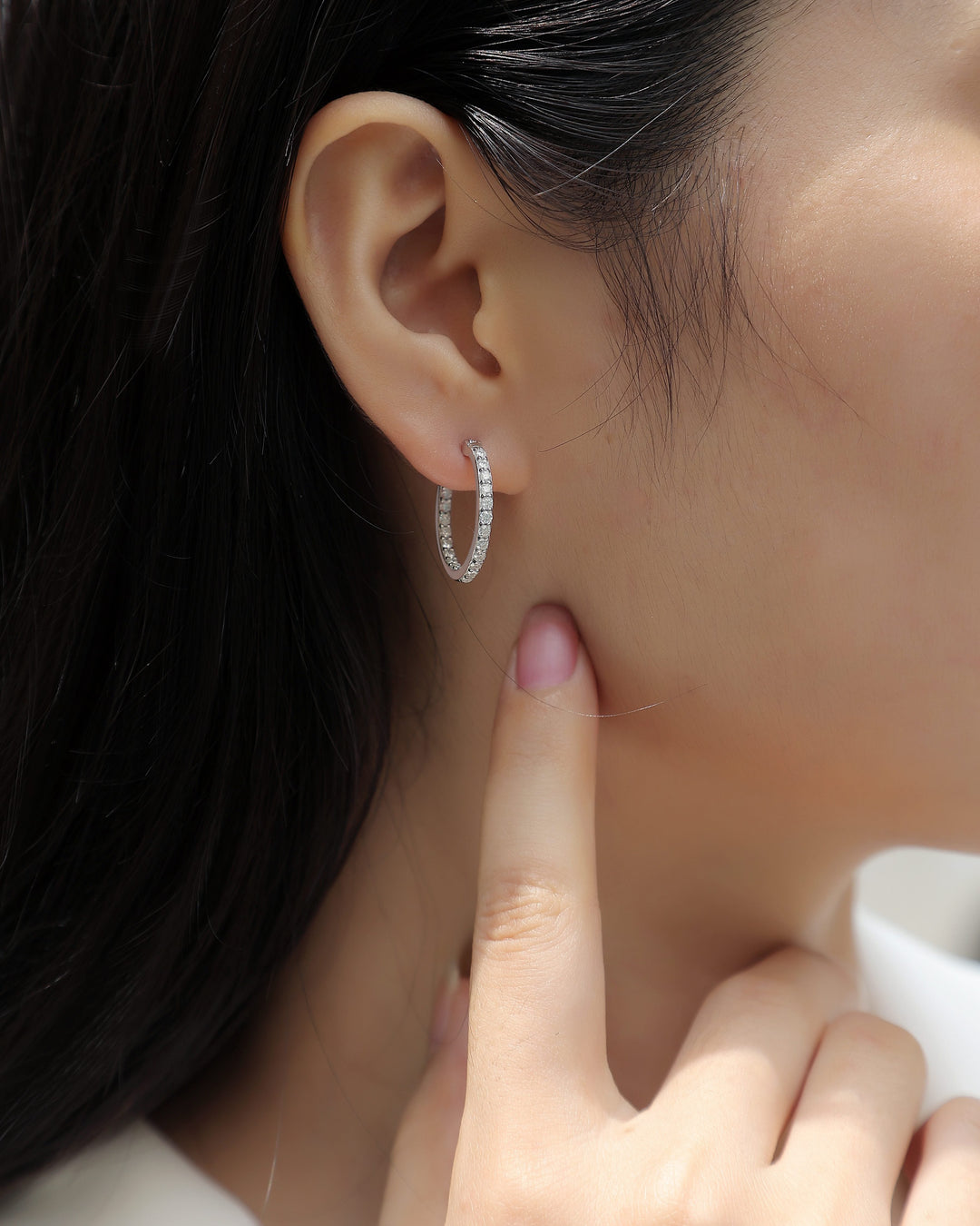 Close-up of a person wearing a silver hoop earring with a blurred background