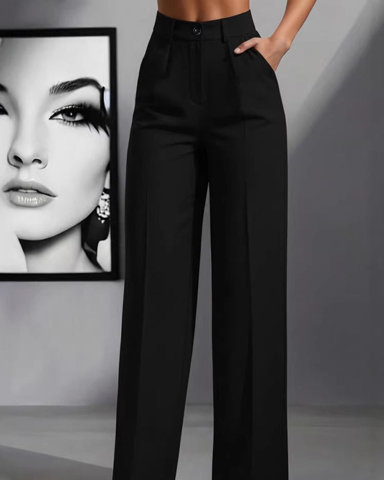 Person wearing black high-waisted pants with a framed portrait in the background.