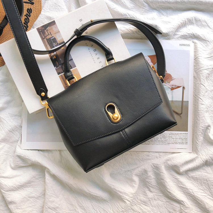 Black handbag with gold accents on a magazine