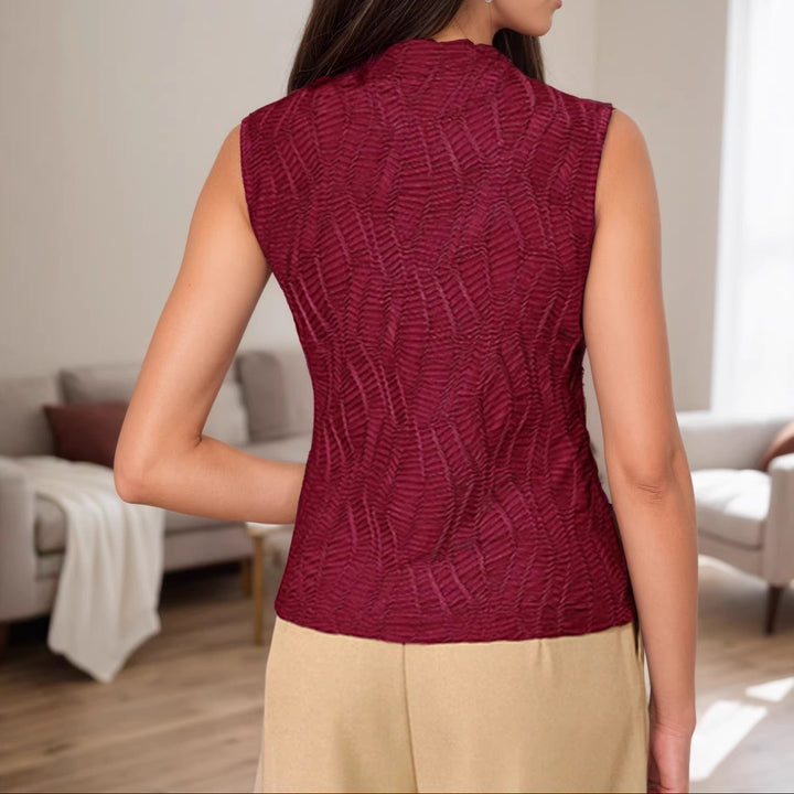 Woman wearing a maroon sleeveless top in a living room setting