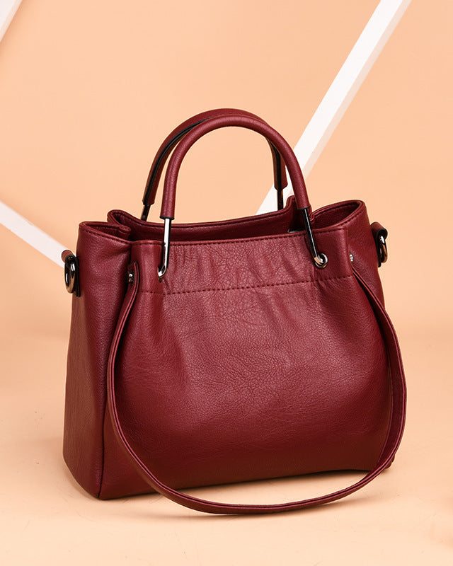 Red handbag on a beige background with a pink flower