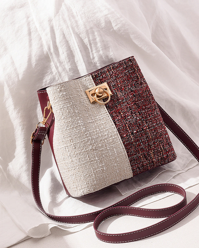 Two-tone handbag with a gold clasp on a white fabric background