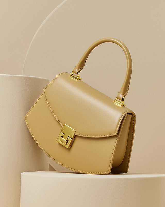 Beige handbag with gold accents on a beige background