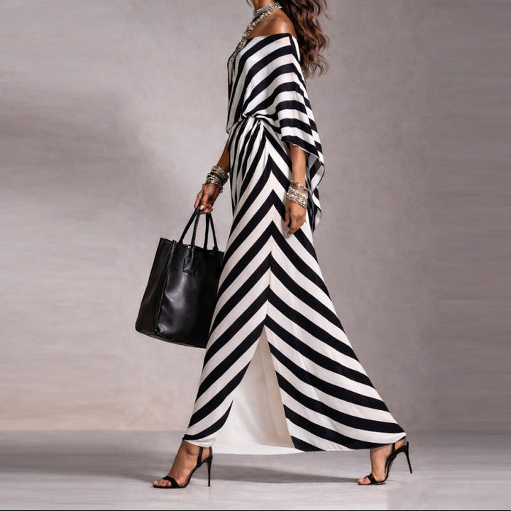Woman wearing a black and white striped dress holding a black handbag against a gray background