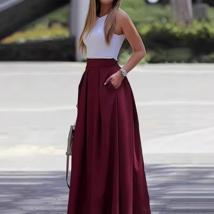Woman wearing a white top and burgundy skirt standing outdoors.