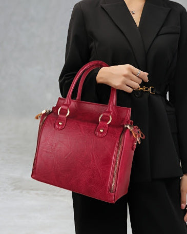 Person holding a red handbag against a gray background