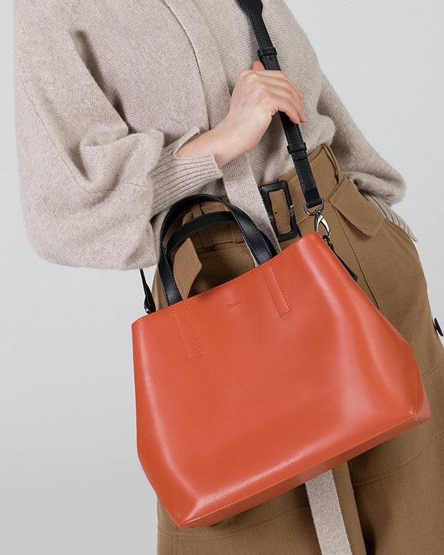Person holding a red handbag against a plain background